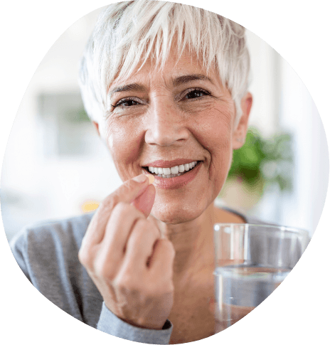Senior woman holding pill and glass of water