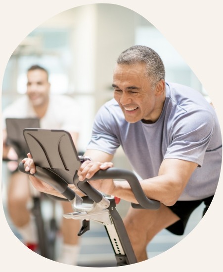 Smiling older man exercising on machine at gym