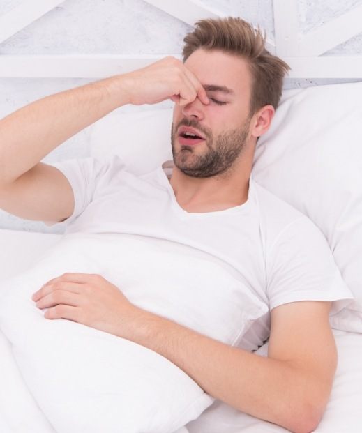 Man lying awake in bed needing insomnia treatment in Denton