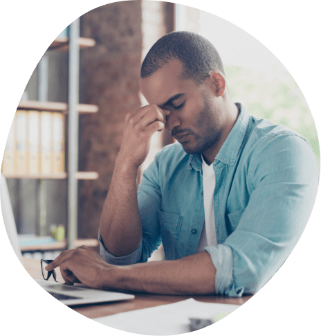 Man sitting at desk pinching bridge of nose