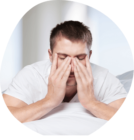 Man rubbing his eyes while sitting in bed