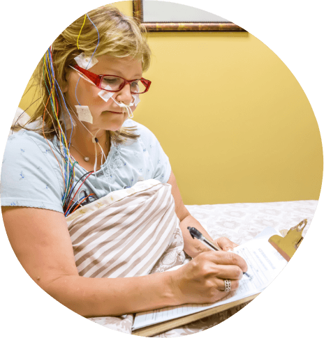 Woman writing on clipboard during sleep apnea test