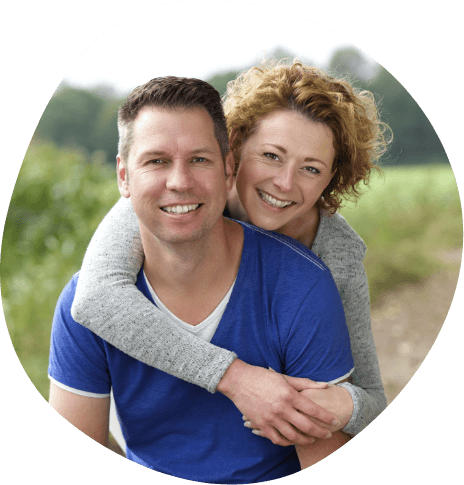 Smiling man and woman holding each other outdoors