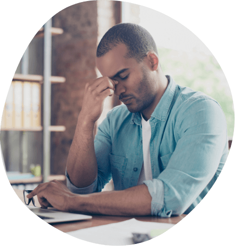 Man sitting at desk pinching bridge of nose