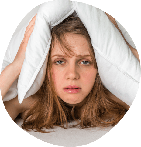 Tired woman in bed covering top of her head with pillow