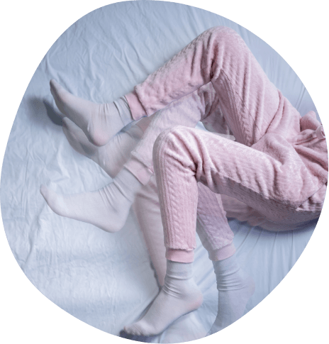 Legs wearing pink pajama pants kicking in bed