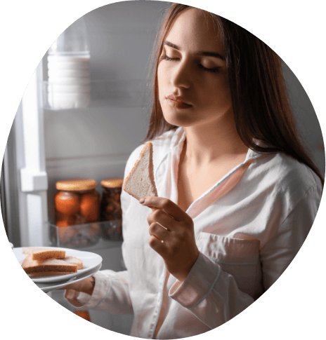 Sleepwalking woman eating bread in kitchen