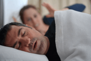 Man snoring in bed wakes up his wife